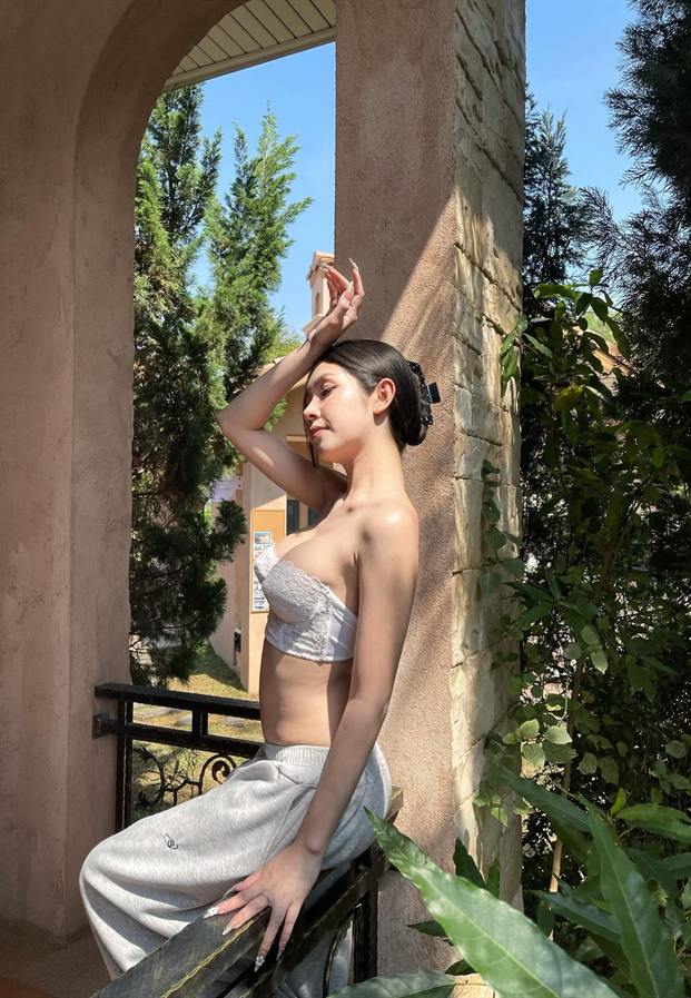 Linlada Chaloemphop ยืนพิงระเบียงวิลล่ากลางแดด