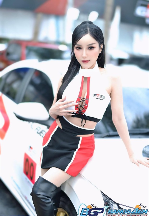 ภัทรภร สุภัทรศักดา ในชุดพริตตี้ยืนข้างรถแข่งสีขาว