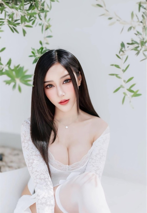 ภัทรภร สุภัทรศักดา ในชุดลูกไม้สีขาวกับฉากใบไม้เขียว