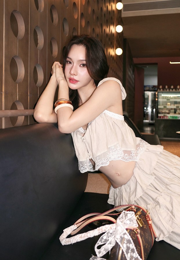 นางแบบสาวยืนริมสะพานในลุคชุดยาวโทนน้ำตาล