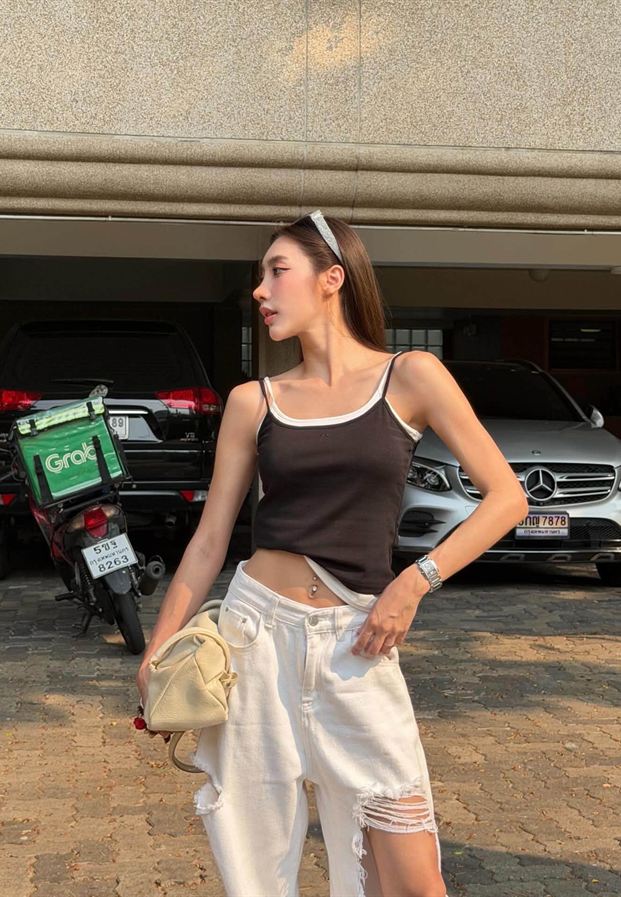 ยืนริมถนนในเสื้อกล้ามสีดำกับกางเกงขากว้างสีครีม