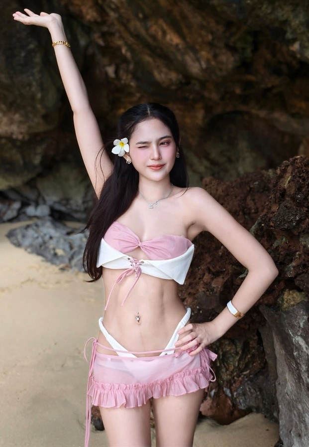 ยกแขนโพสท่าริมโขดหินในชุดว่ายน้ำโทนชมพูขาว
