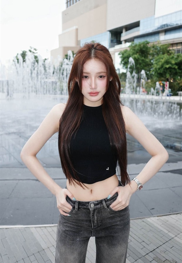 ยืนหน้าน้ำพุในเสื้อกล้ามสีดำกับยีนส์ขากระบอก