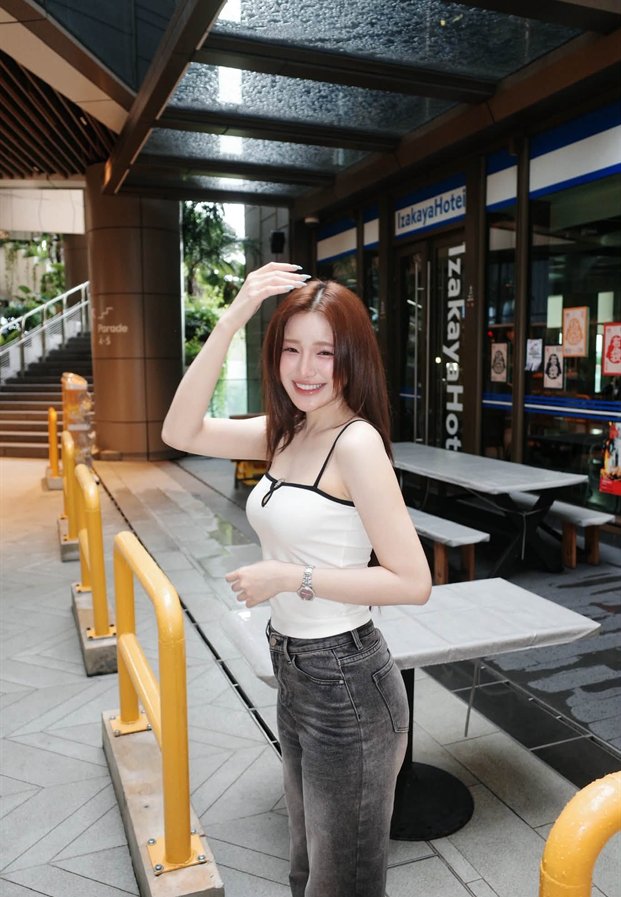 ขนม Khanomwws ในเสื้อสายเดี่ยวสีขาวหน้าร้านย่านใจกลางเมือง