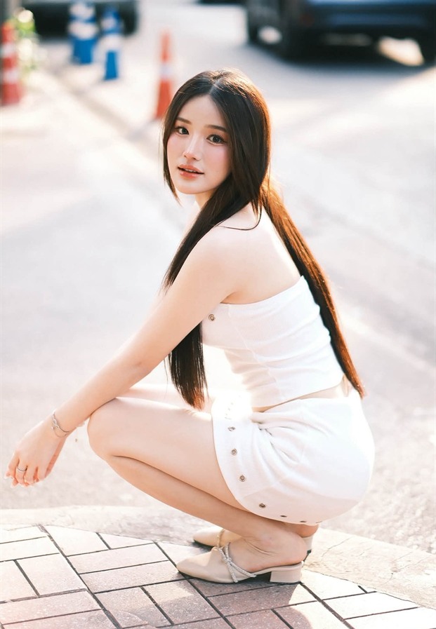 นั่งยองริมทางเท้าในชุดสีขาว