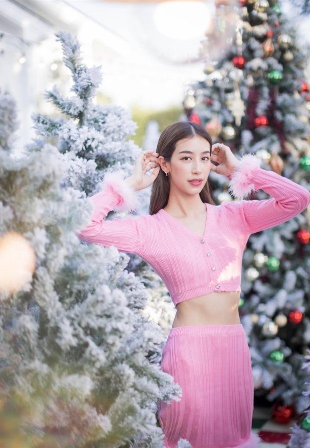 Mint Chalida ในชุดสีชมพูหน้าต้นคริสต์มาส