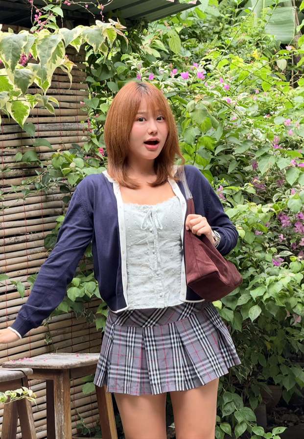 ยืนหน้ากำแพงต้นไม้ในกระโปรงลายสก๊อต