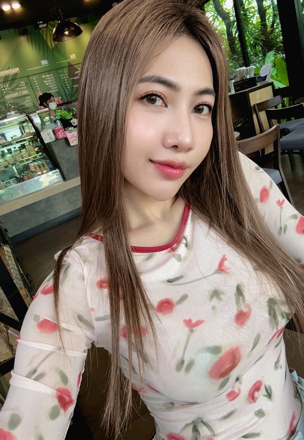 ภัทรนันท์ พันธ์นาค สวมเสื้อแขนยาวสีขาวพิมพ์ลายดอกกุหลาบแดงขอบคอสีแดงในร้านคาเฟ่